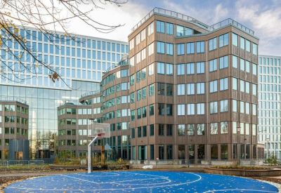 Blue outdoor sports court situated in front of a multi-story glass office complex.