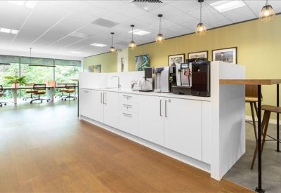 Modern kitchen area with white cabinetry, coffee machine, and pendant lighting.