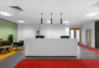 Minimalist reception area with a white desk, red floor runners, and lounge seating.