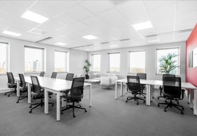 Bright open-plan office with white desks, black ergonomic chairs, and a red feature wall.