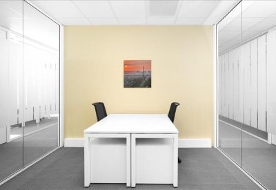 Minimalist private meeting room with a white table and views through glass partitions.