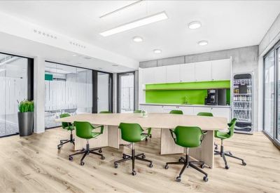 Breakout area with a large light wood table and lime green kitchen backsplash.