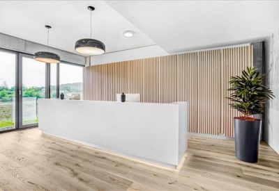 Sleek white reception desk set against a light wood paneled wall.