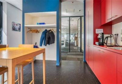 Breakout space with a wooden high table and a vibrant blue accent wall.