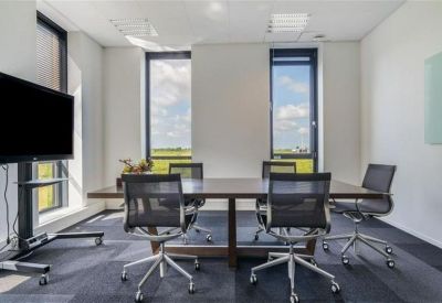 Professional meeting room with a dark wood table and black mesh chairs.