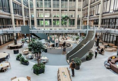 Spacious multi-level atrium with central café, curved staircases, and indoor trees.