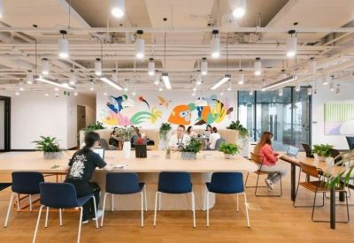 Bright open-plan office space featuring a large wooden communal desk and colorful wall mural.
