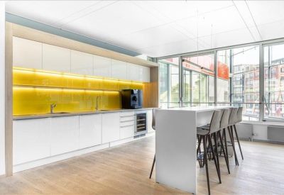 Modern communal kitchen area with a yellow backsplash and white breakfast bar.