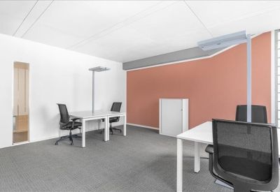 Bright private office featuring white desks and a coral-colored accent wall.