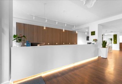 Minimalist reception desk with warm under-counter lighting and wood panelled feature wall.