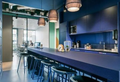 Modern communal kitchen and breakfast bar with dark blue cabinetry and designer pendant lights.