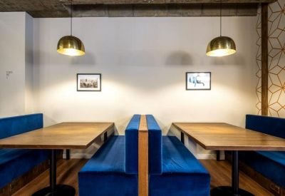 Plush blue velvet booths with wooden tables under brass pendant lights.