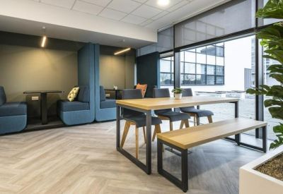 Modern breakout area featuring blue high-back seating booths and a light wood table.