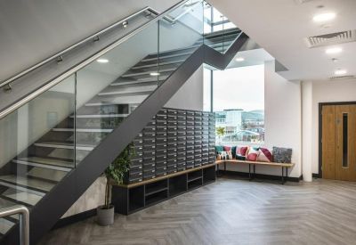 Modern lobby area with a glass-balustrade staircase and a wall of secure mailboxes.