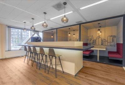 Modern communal break area with a tall breakfast bar and integrated booth seating with red cushions.