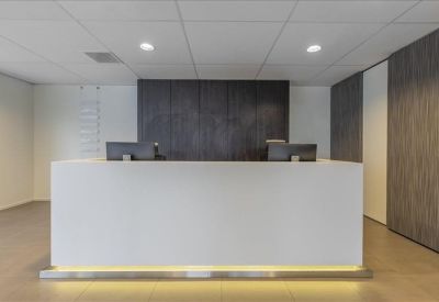 Minimalist white reception desk with warm under-lighting and dark wood-paneled walls.