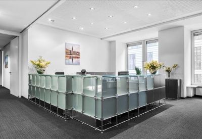 Professional reception area with a frosted glass front desk and vibrant flowers.