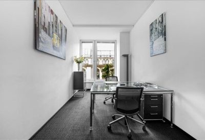 Bright private office with glass desk, ergonomic chairs, and wall art.