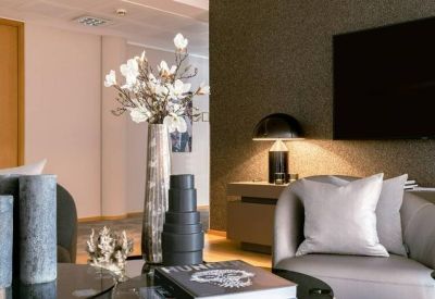 Sophisticated lounge area with a grey armchair and decorative floral vase.