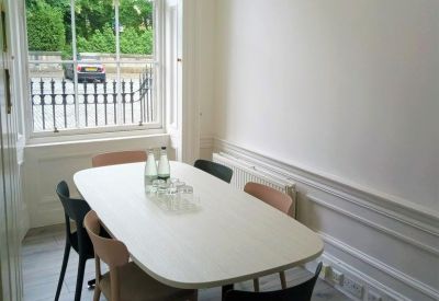 Bright dining area with a white table and views of a green park.