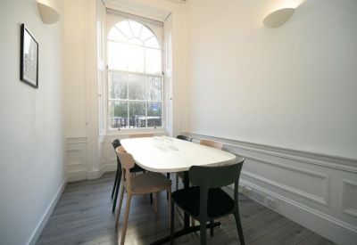 Bright meeting room with a white table and wooden chairs.
