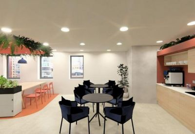 Modern communal kitchen and dining area featuring navy chairs and light wood cabinetry.