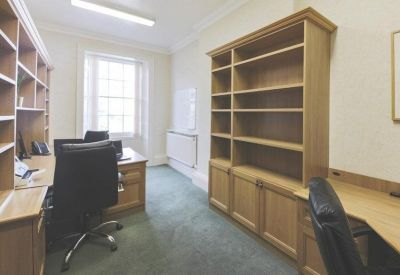 Bright private office suite with built-in wooden bookshelves and desk space.