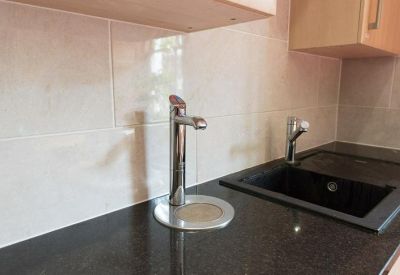 Modern communal kitchen area with black countertops and chrome fixtures.