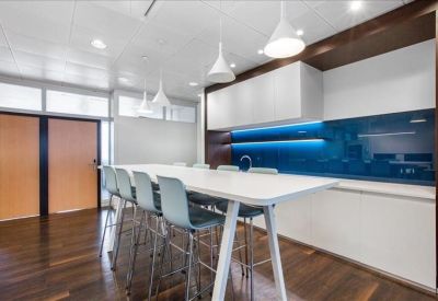 Breakout area featuring a long high-top table, blue stools, and a vibrant blue backsplash with integrated lighting.