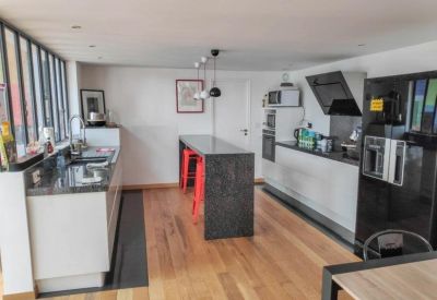 Modern kitchen with sleek black countertops and vibrant red stools.