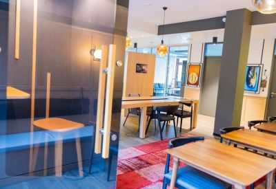 Coworking area with wooden tables and chairs on a red patterned rug.