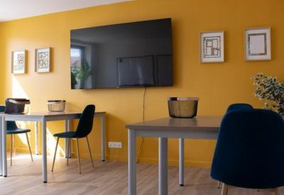 Communal area featuring a vibrant yellow wall and wall-mounted television.