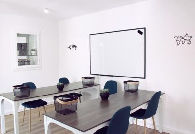 Sleek coworking space with long white tables and dark blue seating.