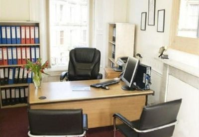 Private office suite featuring a wooden desk, black leather chairs, and a fireplace.