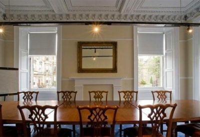 Grand boardroom with a long wooden table, ornate ceiling, and large windows.