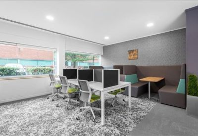 Modern coworking area with grey workstations and a comfortable booth seating area.