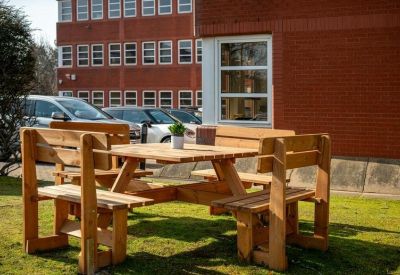 Outdoor seating area with a wooden picnic table on a lawn.