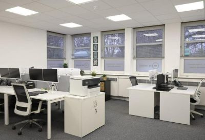 Bright open-plan office with white desks, ergonomic chairs, and large windows.