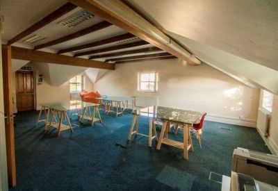 Large open-plan attic office with exposed wooden beams and blue carpeting.