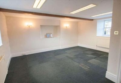 Empty carpeted office space with fluorescent lighting and a recessed wall shelf.