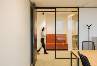 Open office space with modern furniture, featuring high tables and stools for a collaborative work environment.