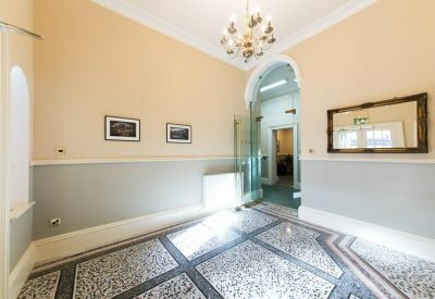Grand reception lobby featuring patterned tile flooring, high ceilings, and an arched doorway.