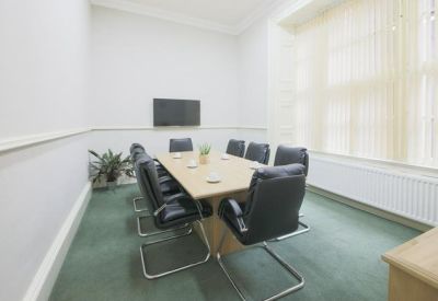 Professional meeting room with a light wood table, black chairs, and large windows.