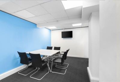 Modern meeting room with a white table, black cantilever chairs, and a blue accent wall.