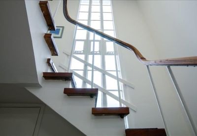Internal staircase with floating wooden treads and a large window for natural light.