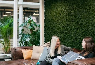 Breakout area with a large green moss wall and comfortable leather seating.