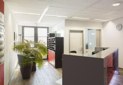 Sleek reception area with a dark desk, wooden floors, and a potted palm.