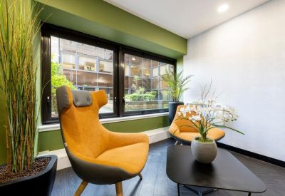Bright lounge area with orange high-back armchairs and green accent walls.