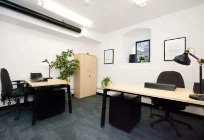 Two-person private office suite with light wood desks and black ergonomic chairs.