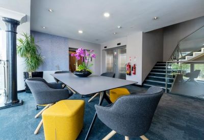 Meeting area with a grey table, stylish yellow and grey chairs, and a decorative column.